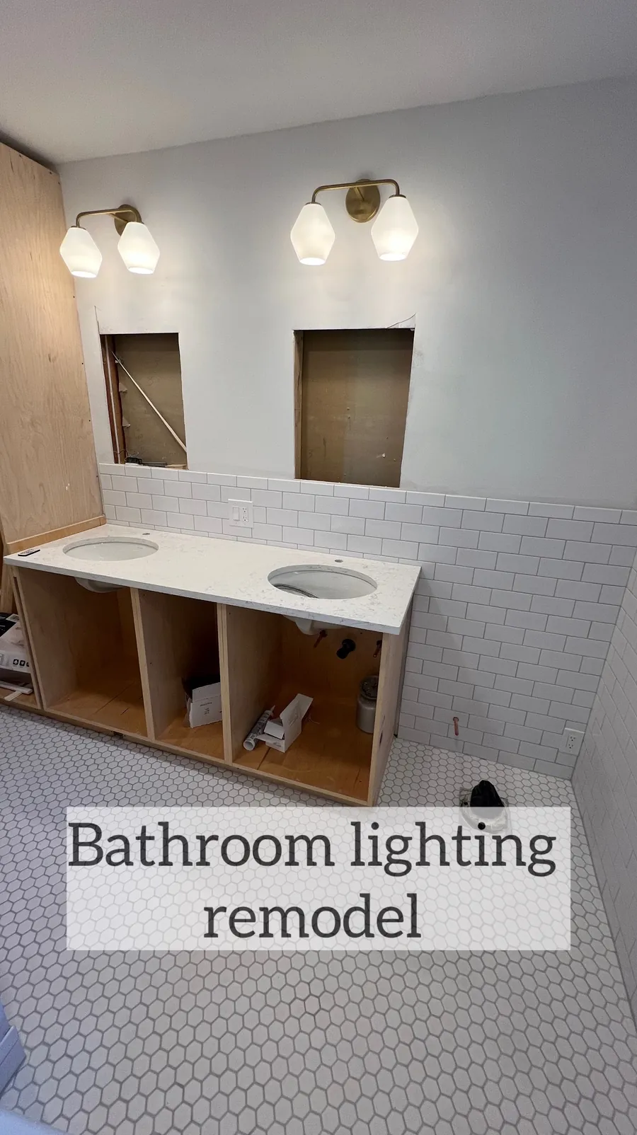 Brass vanity sconce lights installed above a bathroom double vanity